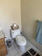 Half bath featuring toilet, tile patterned floors, and baseboards