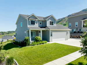 View of front of house with driveway, a front lawn, and a mountain view
