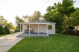 View of front of home featuring a porch, a front yard, concrete driveway, and a chimney