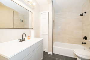 Bathroom featuring tile patterned floors, vanity, tub / shower combination, and toilet