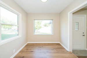 Empty room featuring light wood-style flooring, a textured ceiling, and baseboards