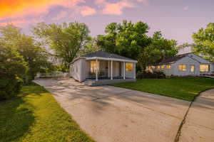 View of front facade with driveway, covered porch, and a yard