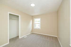 Unfurnished bedroom featuring carpet flooring, baseboards, and a closet