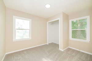 Unfurnished bedroom with light colored carpet and baseboards