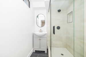 Full bathroom with vanity, a stall shower, tile patterned floors, and baseboards