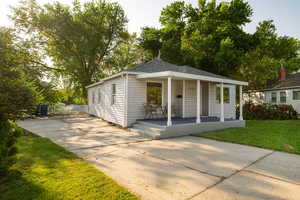 View of front of property with covered porch, a front yard, concrete driveway, and a shingled roof