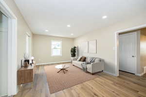 Living area with light wood finished floors, baseboards, and recessed lighting