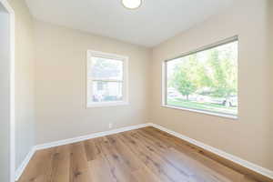 Unfurnished room featuring plenty of natural light, wood finished floors, baseboards, and a textured ceiling