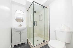 Full bathroom featuring toilet, tile patterned flooring, vanity, and a shower stall