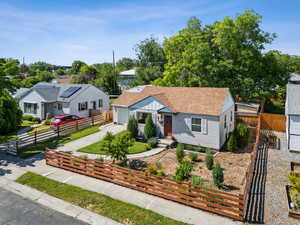 Bungalow with a fenced front yard, driveway, a garage, a shingled roof, and a residential view
