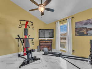 Exercise room with baseboards, marble finish flooring, ceiling fan, and vaulted ceiling