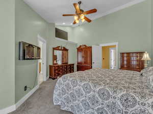 Carpeted bedroom featuring high vaulted ceiling, baseboards, and a ceiling fan