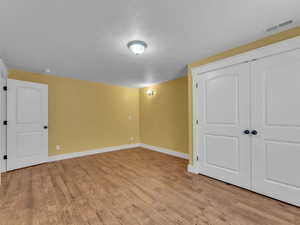 Basement with baseboards, wood finished porcelain tile floors, and a textured ceiling