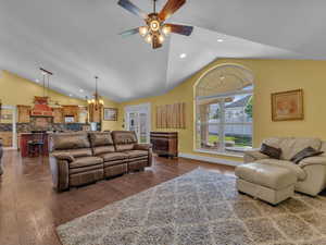 Living area with lofted ceiling, a ceiling fan, a chandelier, dark wood-style floors, and recessed lighting