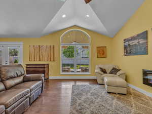 Living area with lofted ceiling, baseboards, plenty of natural light, recessed lighting, and wood finished floors