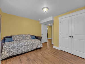 Bedroom with wood finished porcelain tile floors, a closet, a textured ceiling, and baseboards