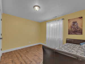 Bedroom with wood finished porcelain tile floors, baseboards, and a textured ceiling