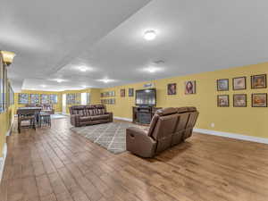 Living room with wood finished porcelain tile floors, a textured ceiling, and baseboards