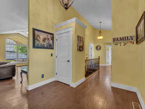 Corridor featuring an upstairs landing, baseboards, wood-type flooring, and high vaulted ceiling