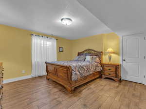 Bedroom with wood finished porcelain tile floors, a textured ceiling, and baseboards