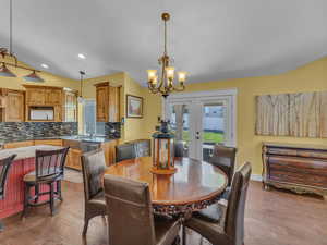 Dining area with french doors, wood finished floors, a chandelier, recessed lighting, and baseboards