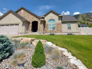 View of front of home with stucco siding, stone siding, an attached garage, concrete driveway, and a mountain view