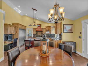Dining space featuring vaulted ceiling, dark wood-style floors, baseboards, a chandelier, and recessed lighting