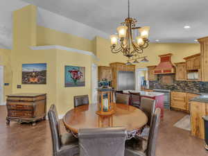Dining space with dark wood finished floors, a chandelier, and high vaulted ceiling