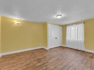 Spare room with a textured ceiling, baseboards, and wood finished porcelain tile floors.