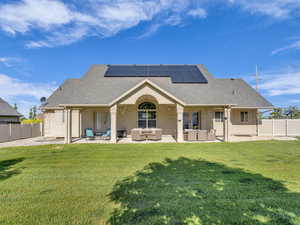 Back of house with outdoor lounge area, roof mounted solar panels, and a shingled roof.