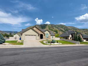 View of front of house with a mountain view, an attached garage, stone siding, driveway, and a residential view