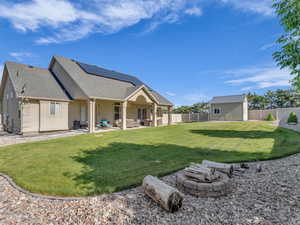 Back of property featuring an outdoor living space with a fire pit, roof mounted solar panels, roof with shingles, a patio, and stucco siding