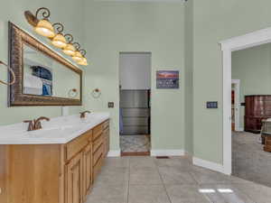 Full bathroom featuring a towering ceiling, double vanity, tile patterned flooring, and baseboards