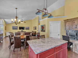 Kitchen with a chandelier, open floor plan, high vaulted ceiling, dark brown cabinets, and wood finished floors