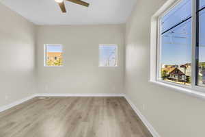 Unfurnished room featuring ceiling fan, light wood-style floors, and baseboards