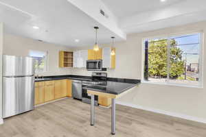 Kitchen featuring appliances with stainless steel finishes, light brown cabinetry, open shelves, light wood-style floors, and recessed lighting