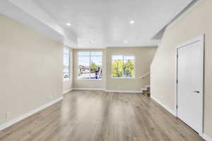 Unfurnished living room with stairs, light wood-style floors, recessed lighting, and baseboards