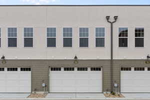 View of front of property with stucco siding, an attached garage, and driveway