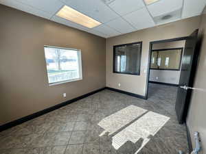 Tiled spare room featuring a paneled ceiling and baseboards