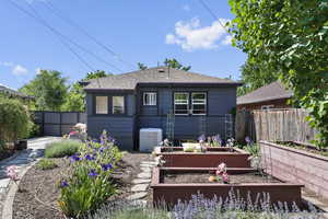 Rear view of house featuring a garden, cooling unit, a fenced backyard, and a shingled roof