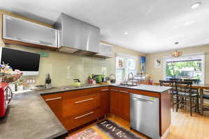 Kitchen featuring appliances with stainless steel finishes, a sink, brown cabinetry, recessed lighting, and a peninsula