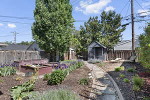 Fenced backyard featuring a garden and an outdoor structure