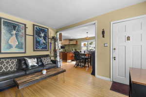 Living area featuring light wood-type flooring, a chandelier, and baseboards