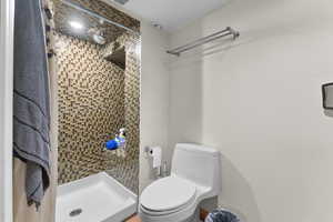 Full bathroom featuring a stall shower and toilet