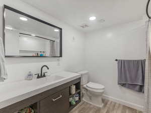 Bathroom featuring wood finished floors, vanity, toilet, recessed lighting, and curtained shower