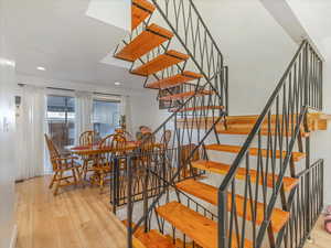 Stairs with hardwood / wood-style floors and recessed lighting