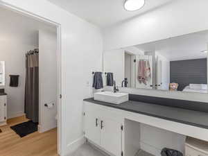 Full bathroom featuring vanity, wood finished floors, baseboards, and toilet