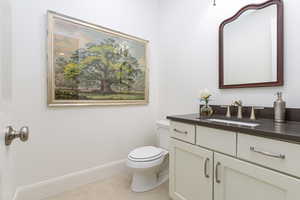 Half bathroom featuring vanity, toilet, and baseboards