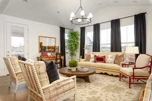 Living area featuring a chandelier, lofted ceiling, wood finished floors, and recessed lighting