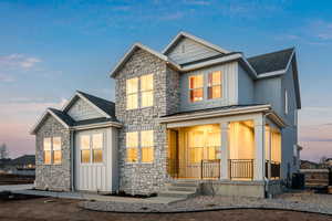 View of front of home with covered porch, stone siding, a standing seam roof, metal roof, and a shingled roof